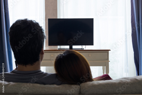 Asian couple watching television on sofa
