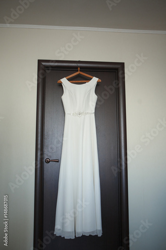 Vertical photo of ivory and white wedding dress hanging on the door