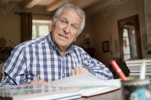 Senior man at home relaxing and writing on notebook