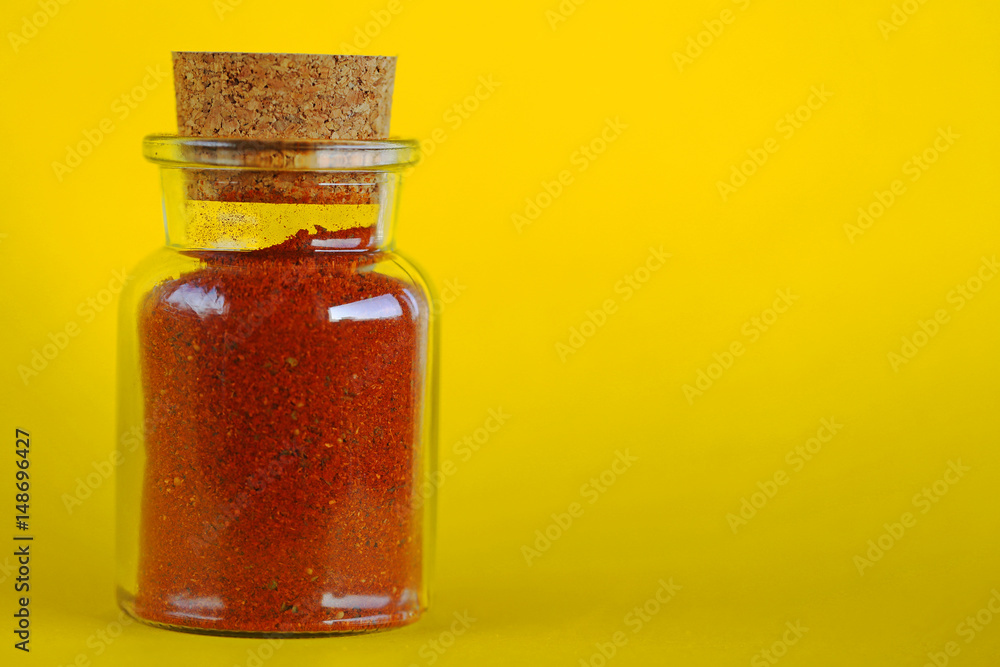 mixture of red chili peppers and paprika in a glass bottle on a yellow background mixture of red chili peppers and paprika in a glass bottle on a yellow background