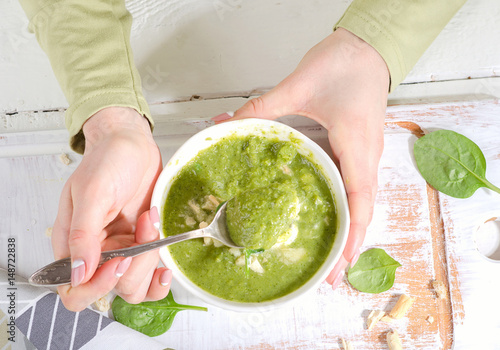 Woman hands with Bowl of green soup.