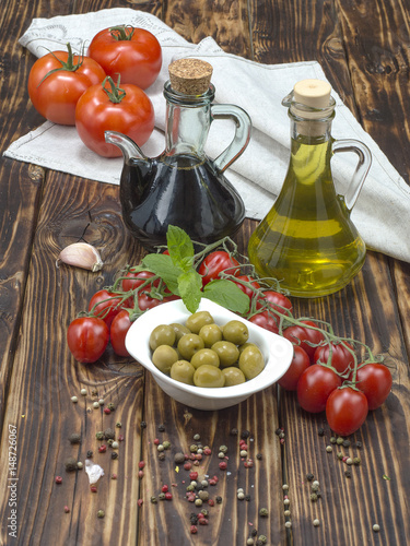 olive oil with olives and tomatoes on a wooden table. 