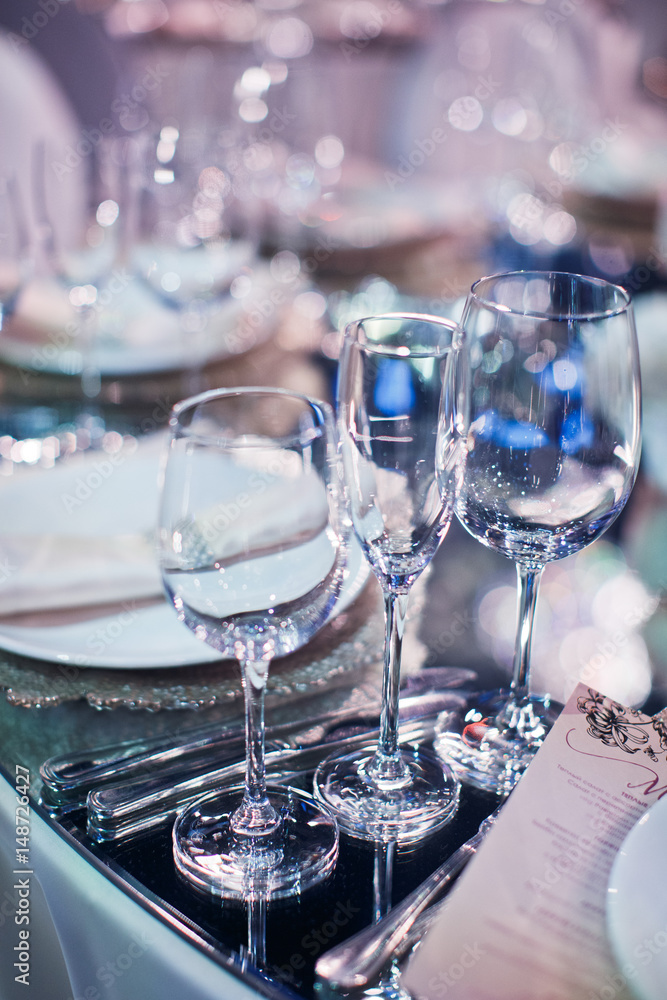 Crystal wineglasses stand before white plates on the dinner table