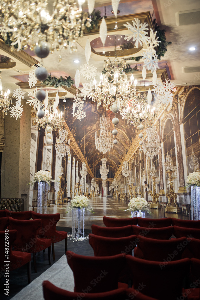 Obraz premium Red soft chairs stand in the rows before wall with picture of luxury corridor on it