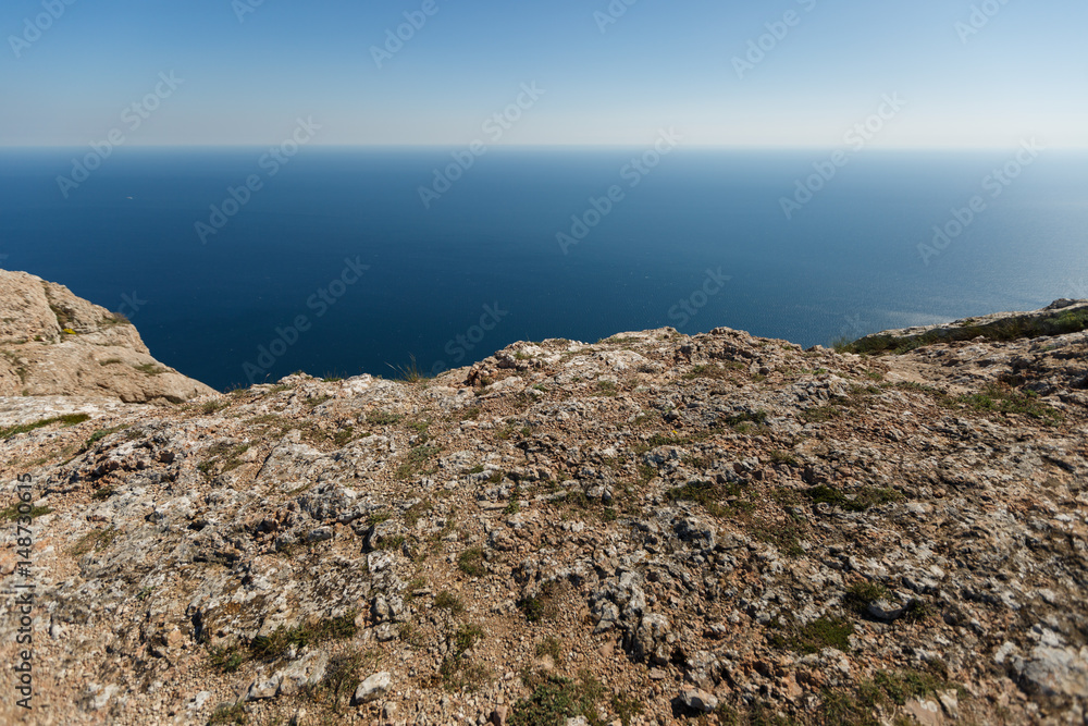Mountain ledge with sea and horizon on background for product placement. Rock edge and steep with blue water on background for designers
