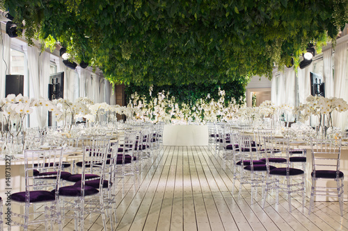 Tables decorated with orchids and violet chairs under green ceiling