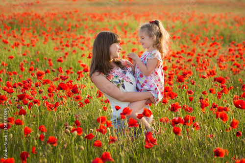 Mother and daughter smiling in a poppy field. The Picnic in the poppy field. Walk with family in poppy field. The cart poppies