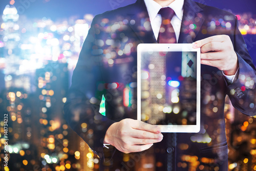 Business man holding tablet on blurry background.