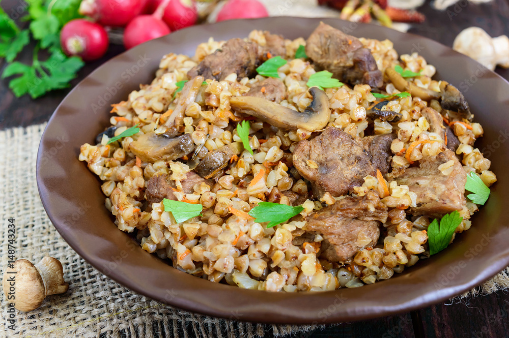 Buckwheat porridge with pieces of meat and mushrooms on a dark wooden background. Close up Buckwheat porridge with pieces of meat and mushrooms on a dark wooden background. Close up