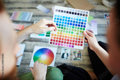 Designer pointing at color palette while discussing it with colleague