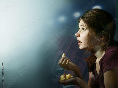teenager girl watching horror movie with pop corn in cinema photo