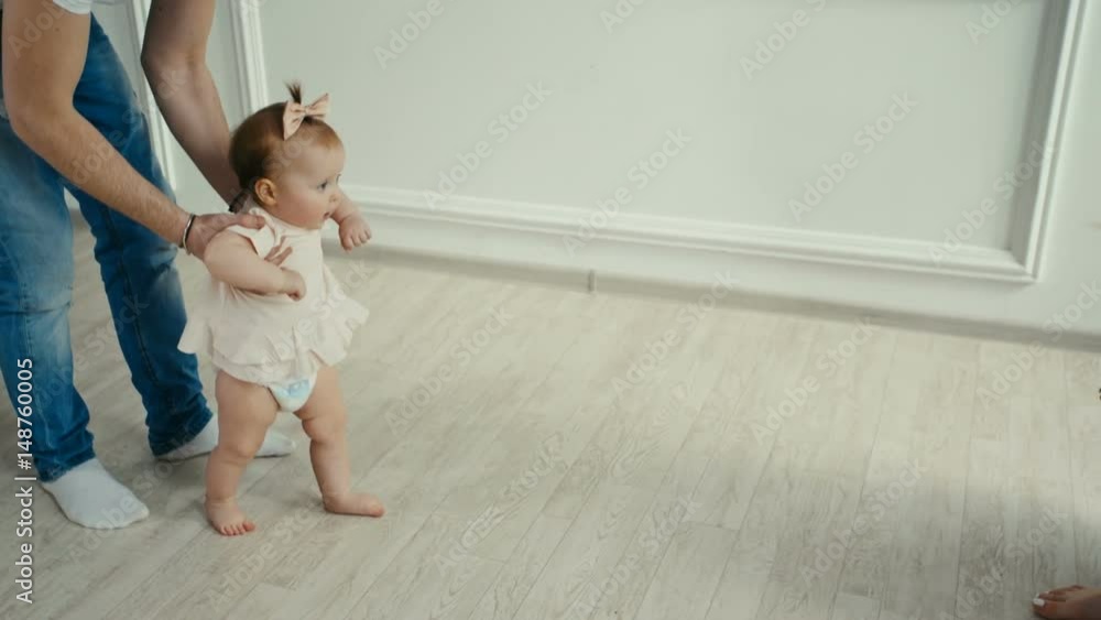 Dad teaches his little daughter to walk. Baby's first steps Dad teaches his little daughter to walk. Baby's first steps