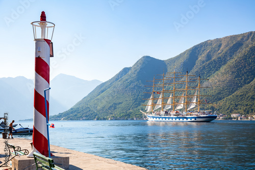 Beautiful sunny day in Perast, Montenegro, big sailing ship is entering the Kotor bay (Boka Kotorska), Montenegro, Europe, old historical town. Lighthouse.