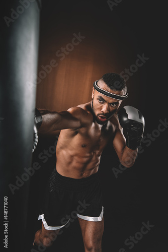 Concentrated young sportsman training thai boxing with punching bag, action sport concept © LIGHTFIELD STUDIOS