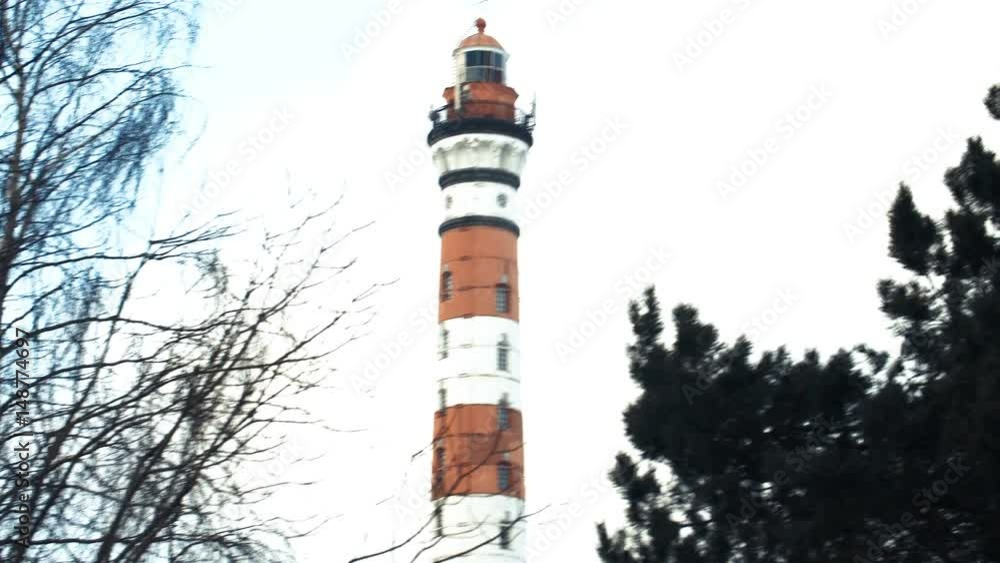 Red and white lighthouse, in winter the trees in the foreground Red and white lighthouse, in winter the trees in the foreground