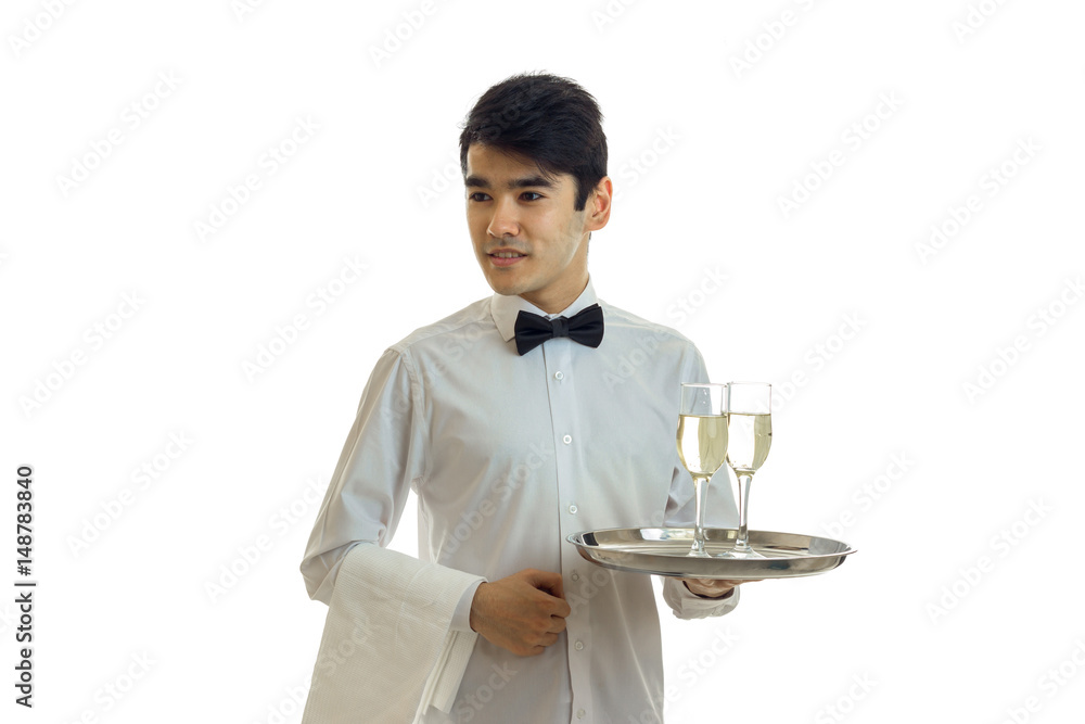 young handsome waiter in a white shirt holding a tray with glasses of champagne young handsome waiter in a white shirt holding a tray with glasses of champagne