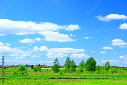 Countryside landscape with agriculture field, village and blue sky with clouds