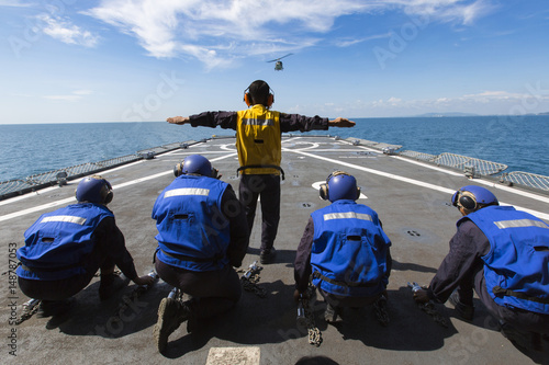 The helicopter is landing on  a signal on warship
 photo