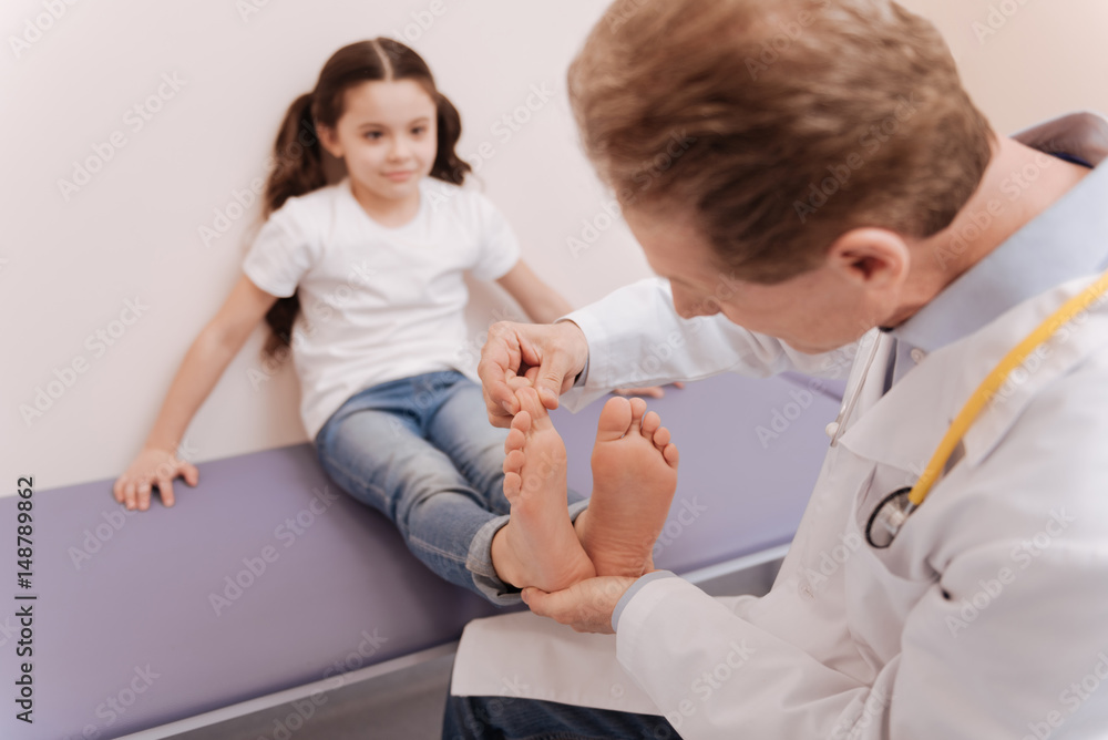 Obraz premium Methodical scrupulous doctor examining girls toes