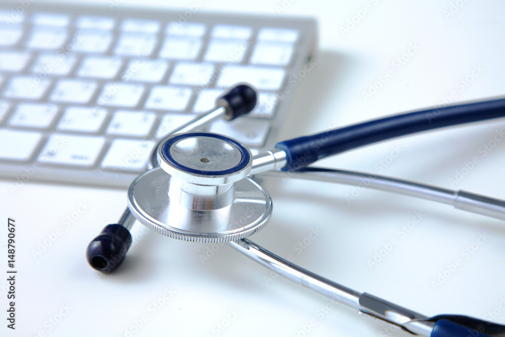 A medical stethoscope near a laptop on a wooden table, on white
