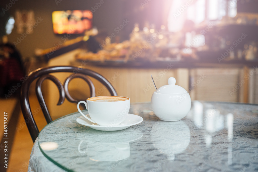 Cup of cappuccino on the table with lace tablecloth. Cozy cafe or restaurant interior. Intentional sun glare Cup of cappuccino on the table with lace tablecloth. Cozy cafe or restaurant interior. Intentional sun glare
