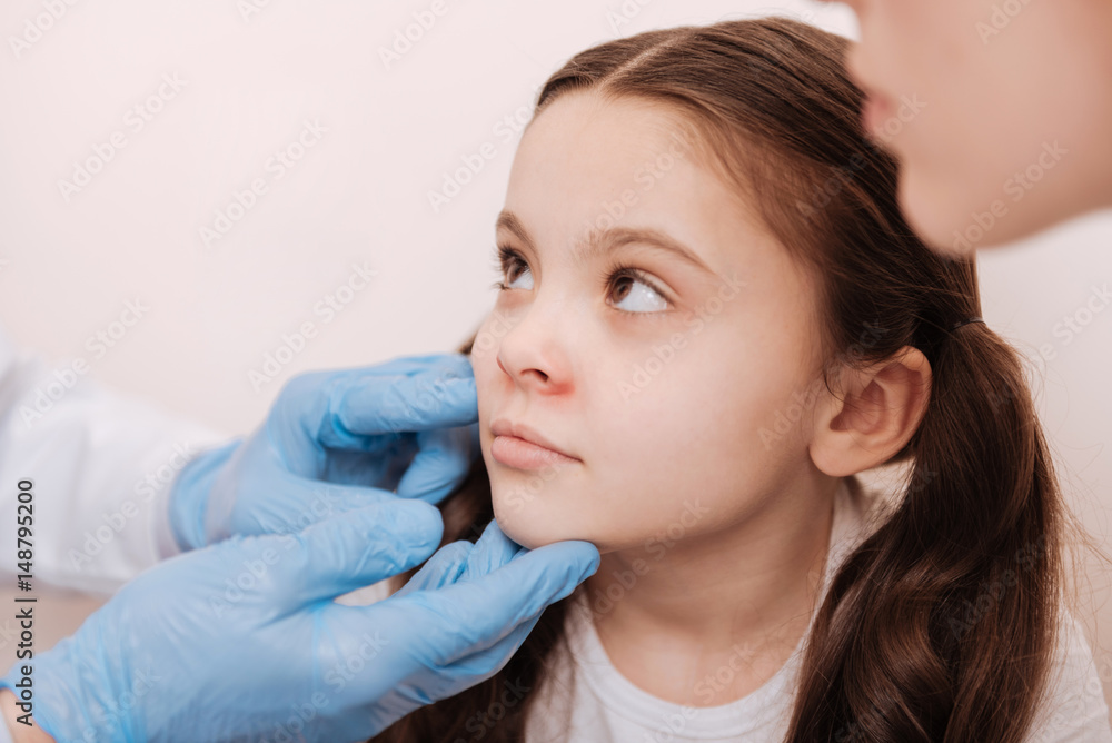 Nice sad child visiting dermatologist with her mom Nice sad child visiting dermatologist with her mom