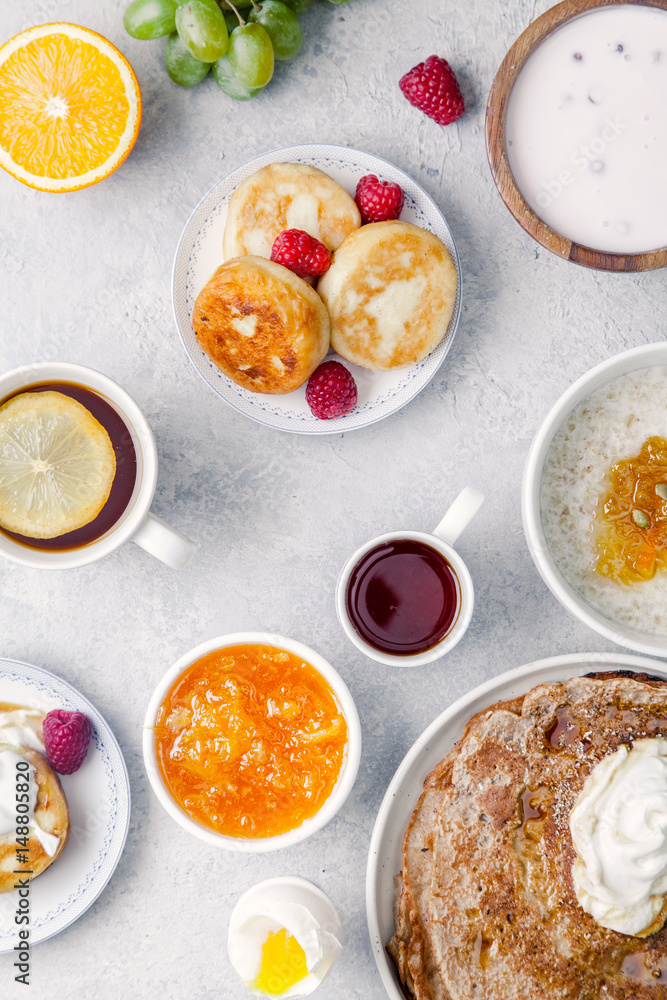 Morning atmosphere. Healthy breakfast with porridge, oatmeal, pancakes, lots of berries and snacks on blue rustic background. Morning atmosphere. Healthy breakfast with porridge, oatmeal, pancakes, lots of berries and snacks on blue rustic background.