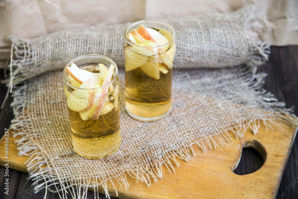 Apple cider with slices of apples in transparent glasses on a wooden board Apple cider with slices of apples in transparent glasses on a wooden board