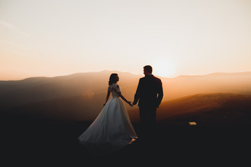 Wedding couple posing on sunset at wedding day. Bride and groom in love