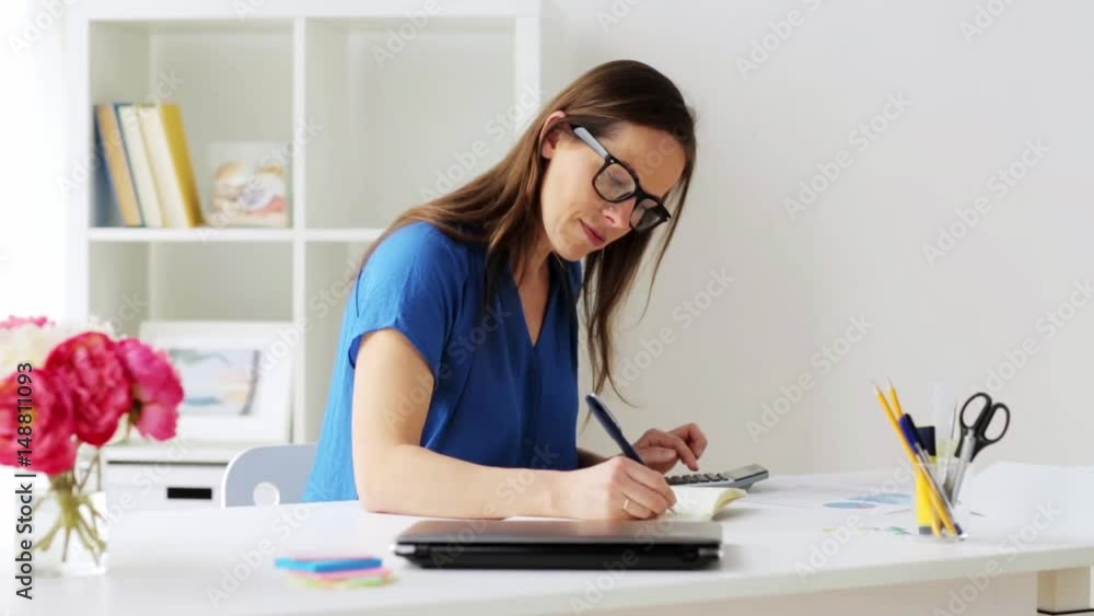 woman with calculator and notebook at office