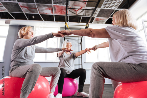 Delighted senior women sitting on fitness balls in a circle