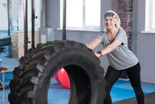 Happy well built woman pushing a huge tire