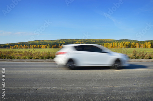White car rides on the road at high speed