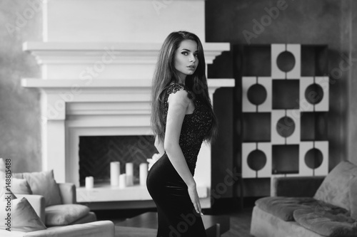 Gorgeous tall slim glamorous woman in long blue lace luxury evening dress standing in lounge interior with wooden floor. Brunnette beautiful stunning girl looking at you. Vogue style portrait