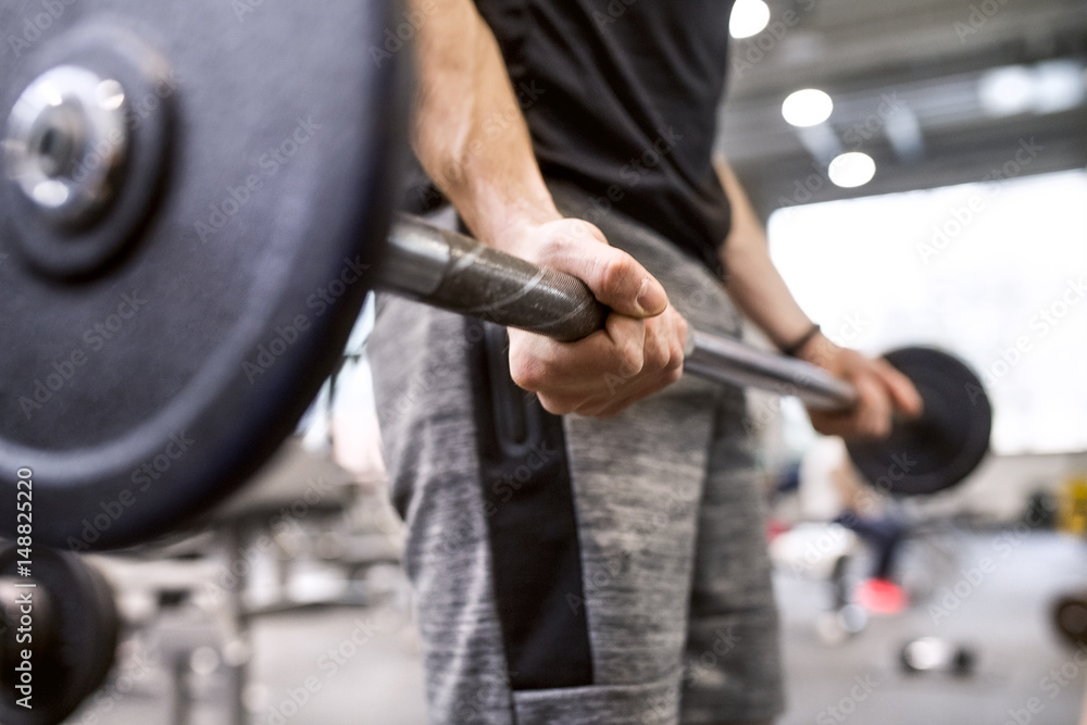 Young man lifting weights in gym Young man lifting weights in gym