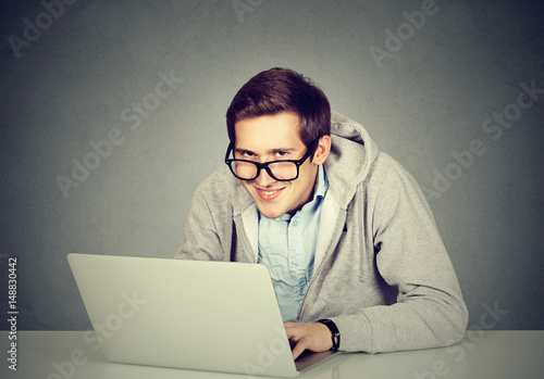 Young sly devious man using a laptop plotting server sabotage