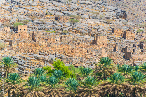 Abandoned village ruins of Riwaygh as-Safil with an oasis underneath on the road between Al Hambra and Jebel Shams, Sultanate of Oman photo