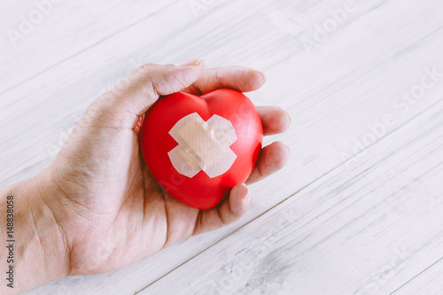 Hand holdind red heart on wooden background