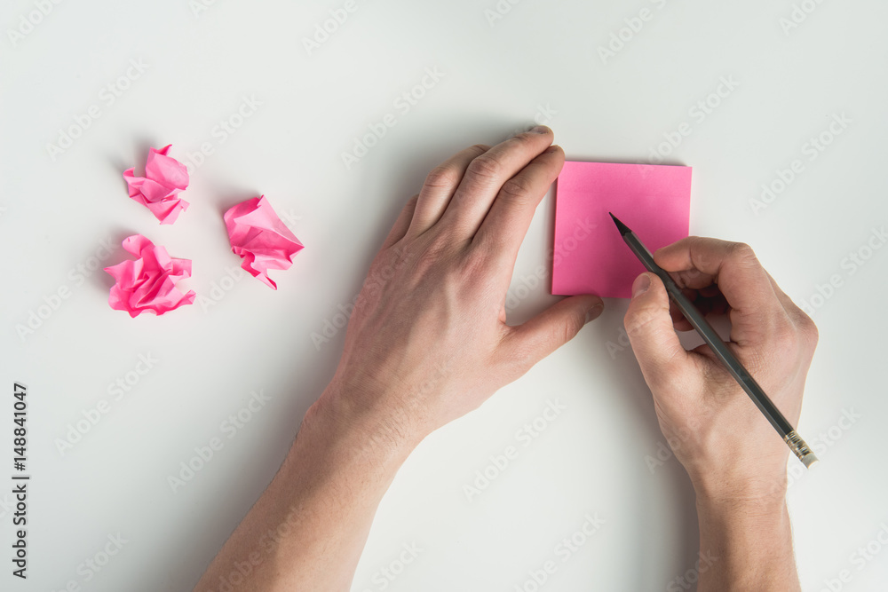 top view of hands holding pencil and blank sticker isolated on white top view of hands holding pencil and blank sticker isolated on white