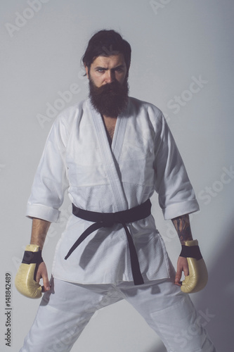 bearded serious karate man in kimono and boxing gloves