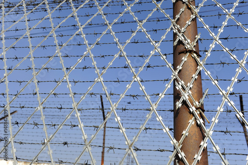 Barbed wire fencing a prison in a sunny day photo