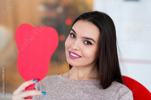 Happy girl looking in the mirror at a smile in the dentistry.