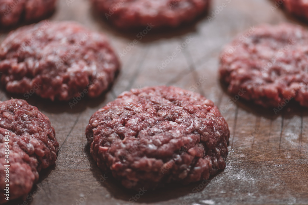 close up view of raw meat patties for burgers on wooden cutting board close up view of raw meat patties for burgers on wooden cutting board