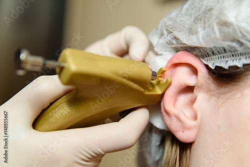 Hardware puncturing the ears of a girl photo