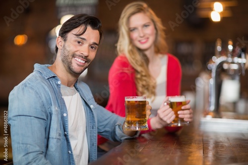 Young man and woman holding beer glasses at pub