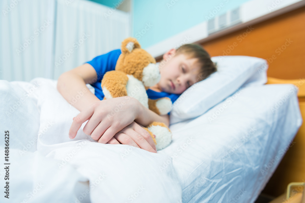 Sick little boy sleeping in hospital bed with teddy bear Sick little boy sleeping in hospital bed with teddy bear