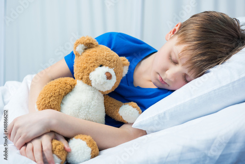 Sick little boy sleeping in hospital bed with teddy bear © LIGHTFIELD STUDIOS