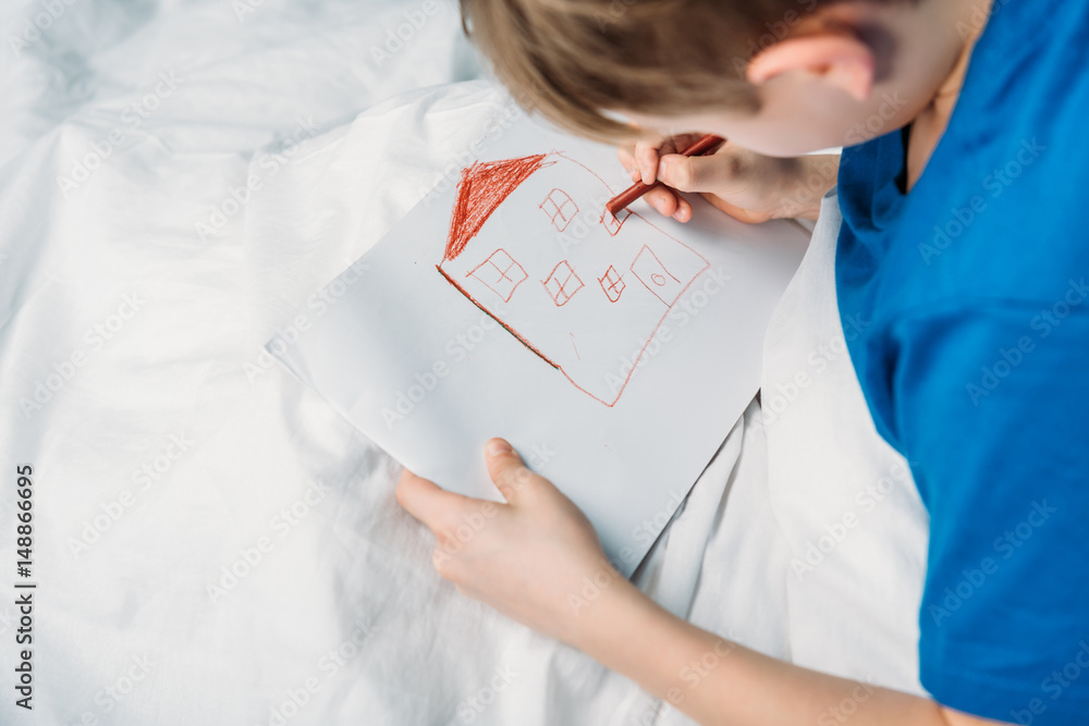 side view of little boy drawing picture while lying in hospital bed side view of little boy drawing picture while lying in hospital bed