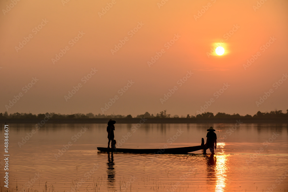 Men fishing on Silhouette a fishing boat in the  River at sun rise