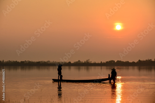Men fishing on Silhouette a fishing boat in the River at sun rise